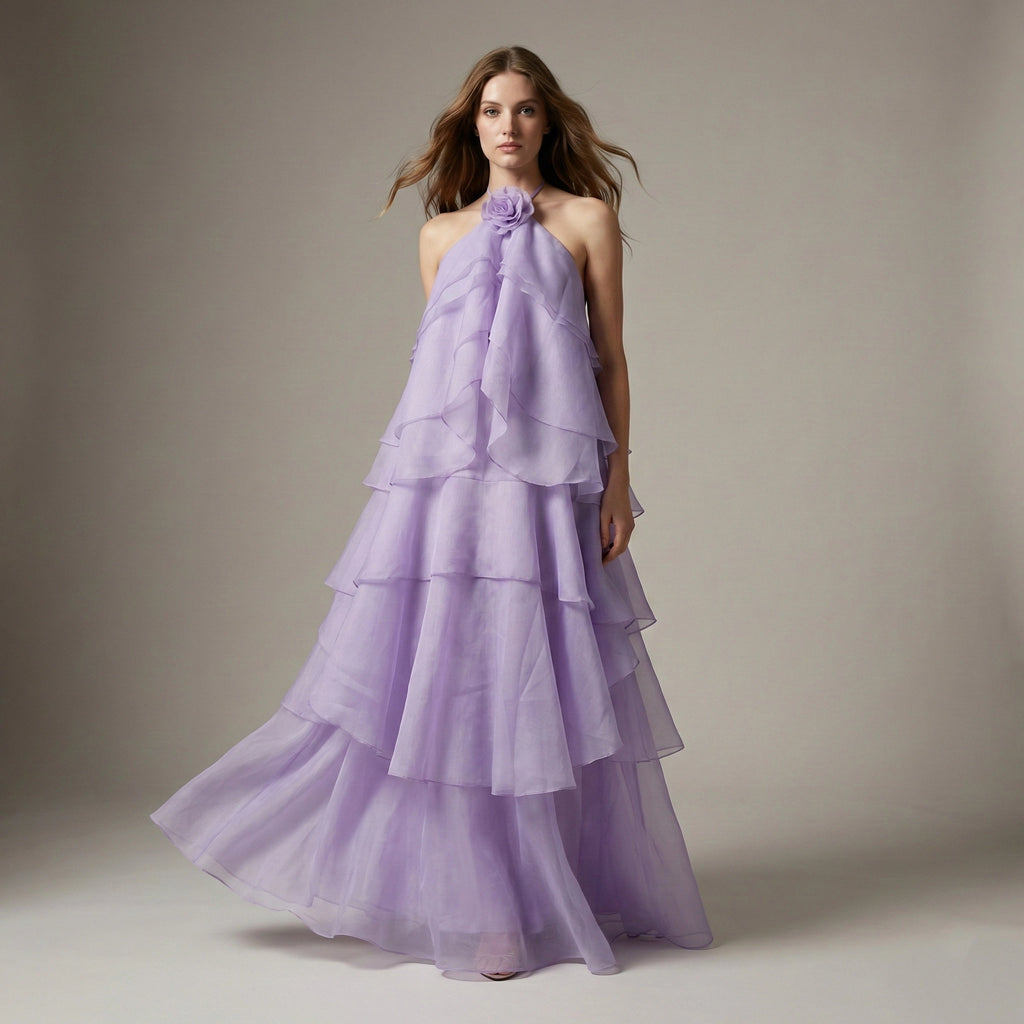 Woman wearing a purple tiered gown against a neutral background
