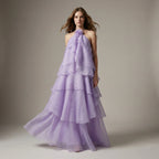 Woman wearing a purple tiered gown against a neutral background