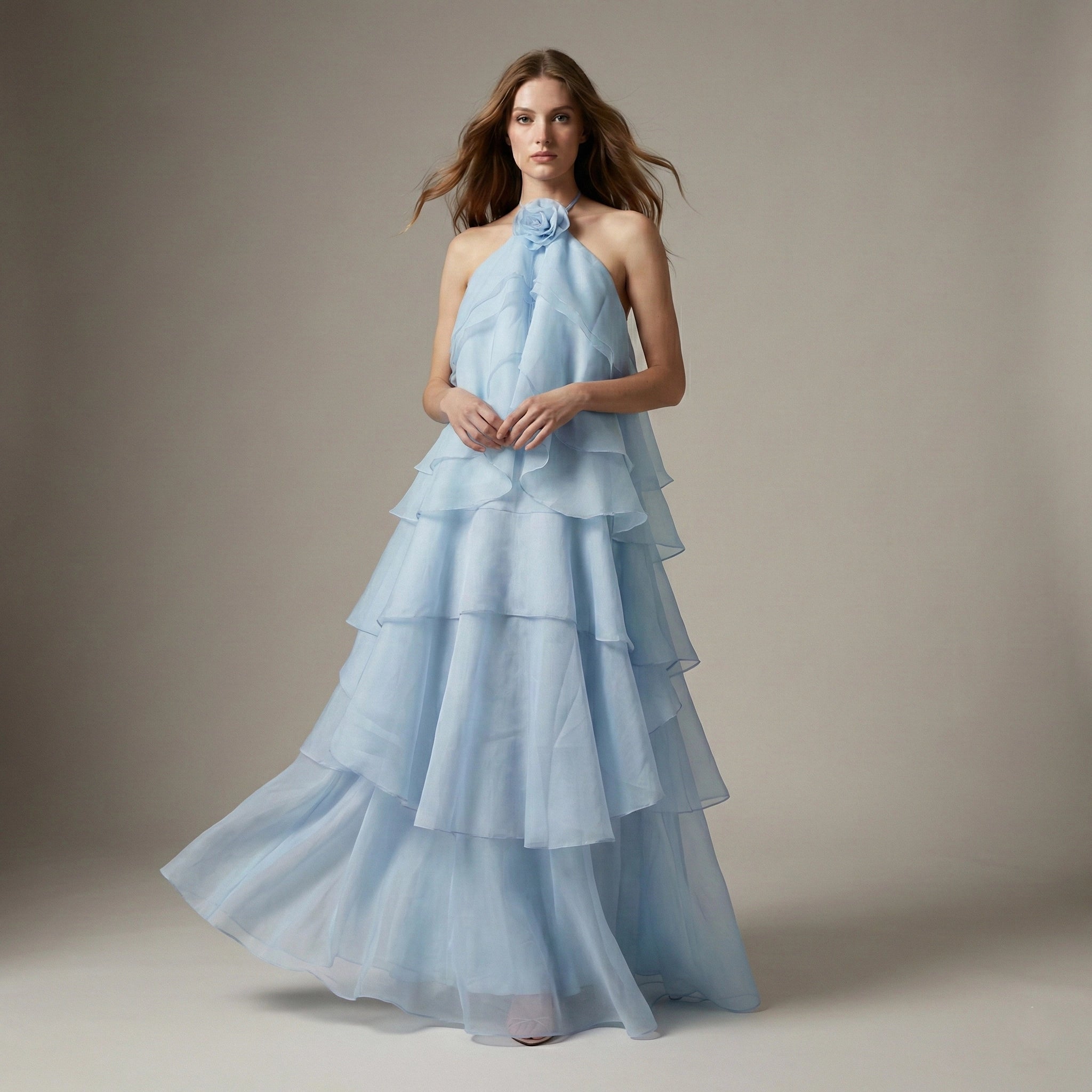 Woman wearing a light blue, tiered gown against a neutral background