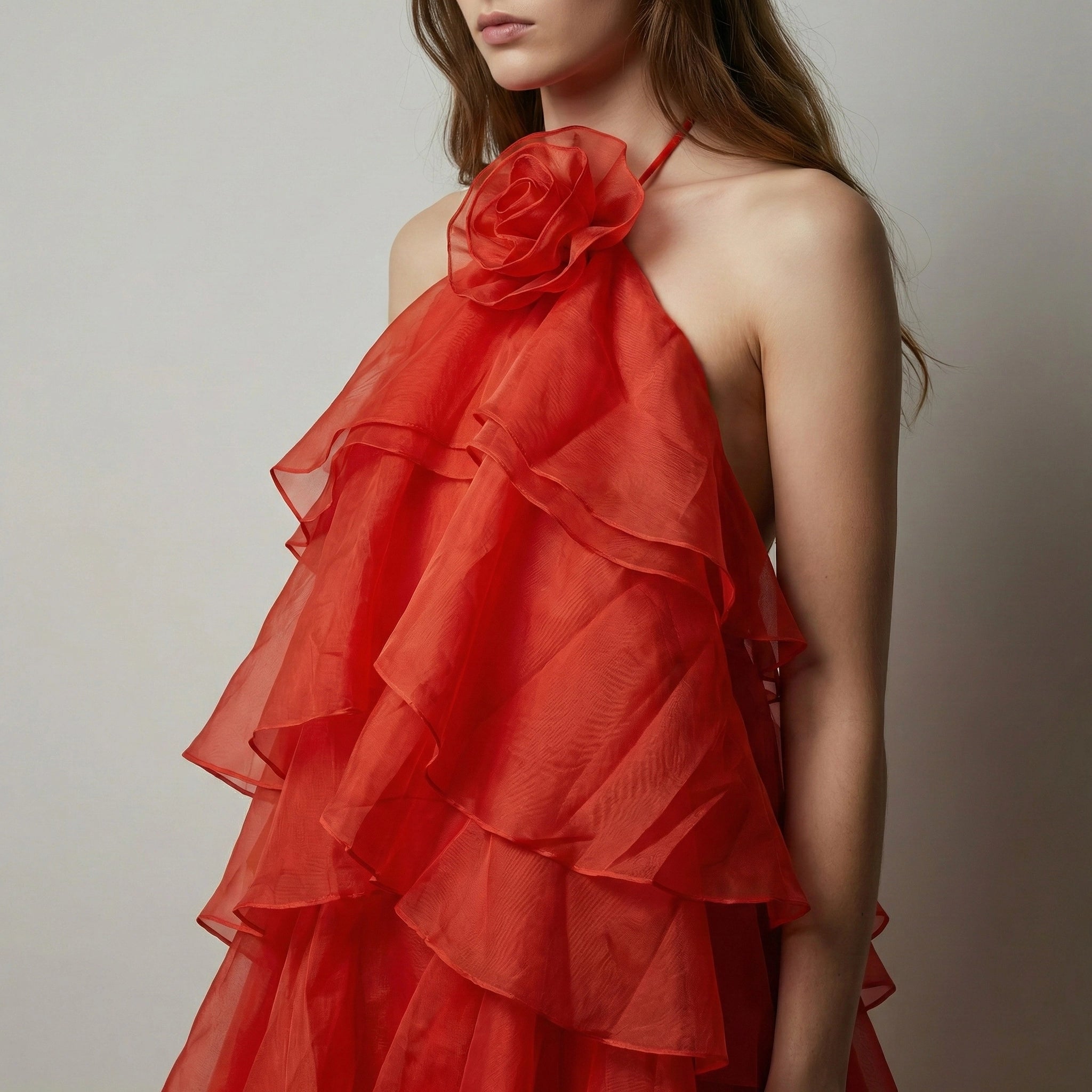 Red ruffled dress with a floral detail on a neutral background