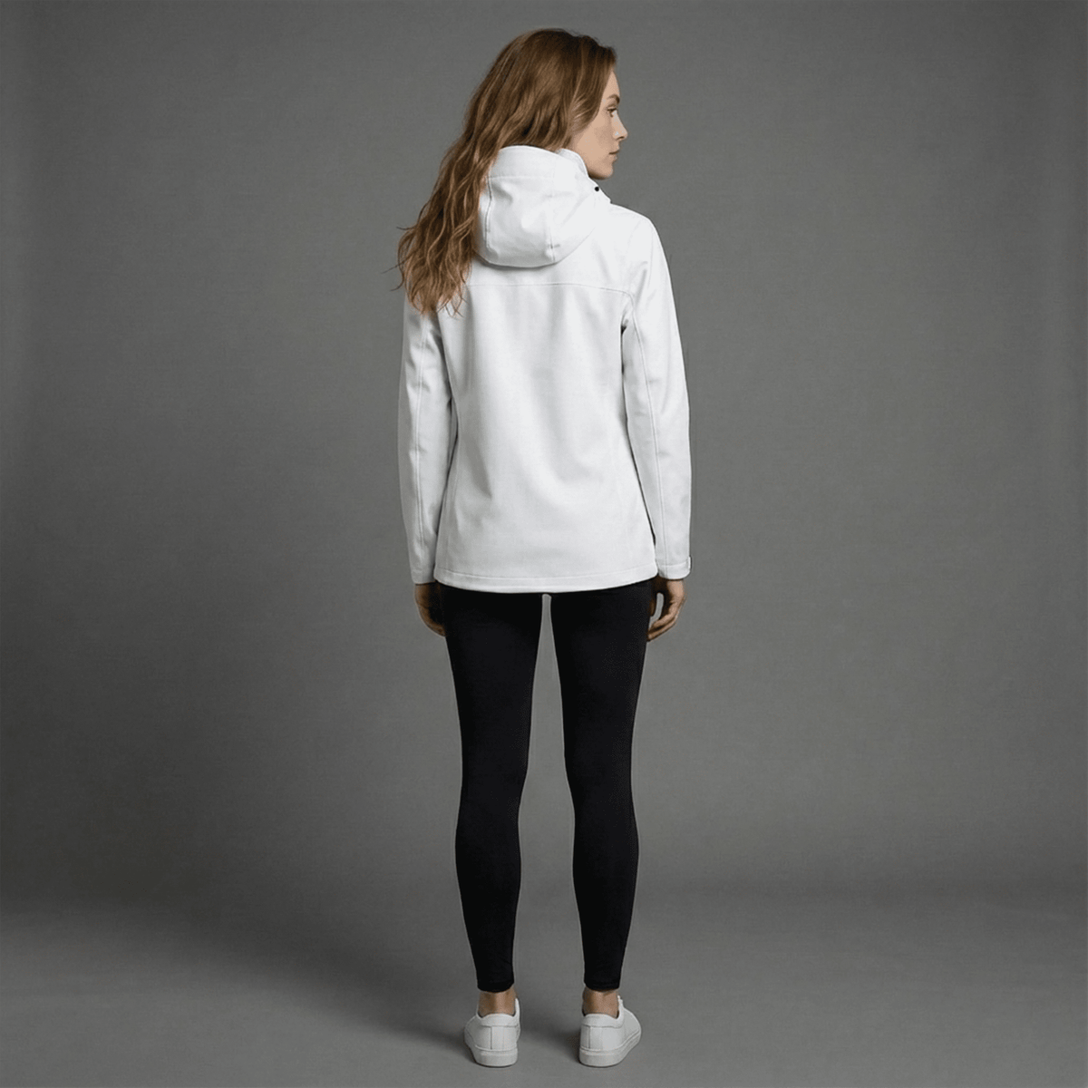 Woman wearing a white jacket and black pants on a gray background