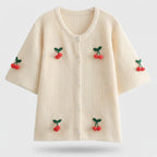 Beige sweater with cherry decorations on a light gray background