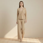 Woman wearing a beige suit with gold buttons on a light gray background