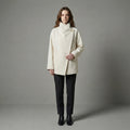 Woman wearing a cream coat against a gray background