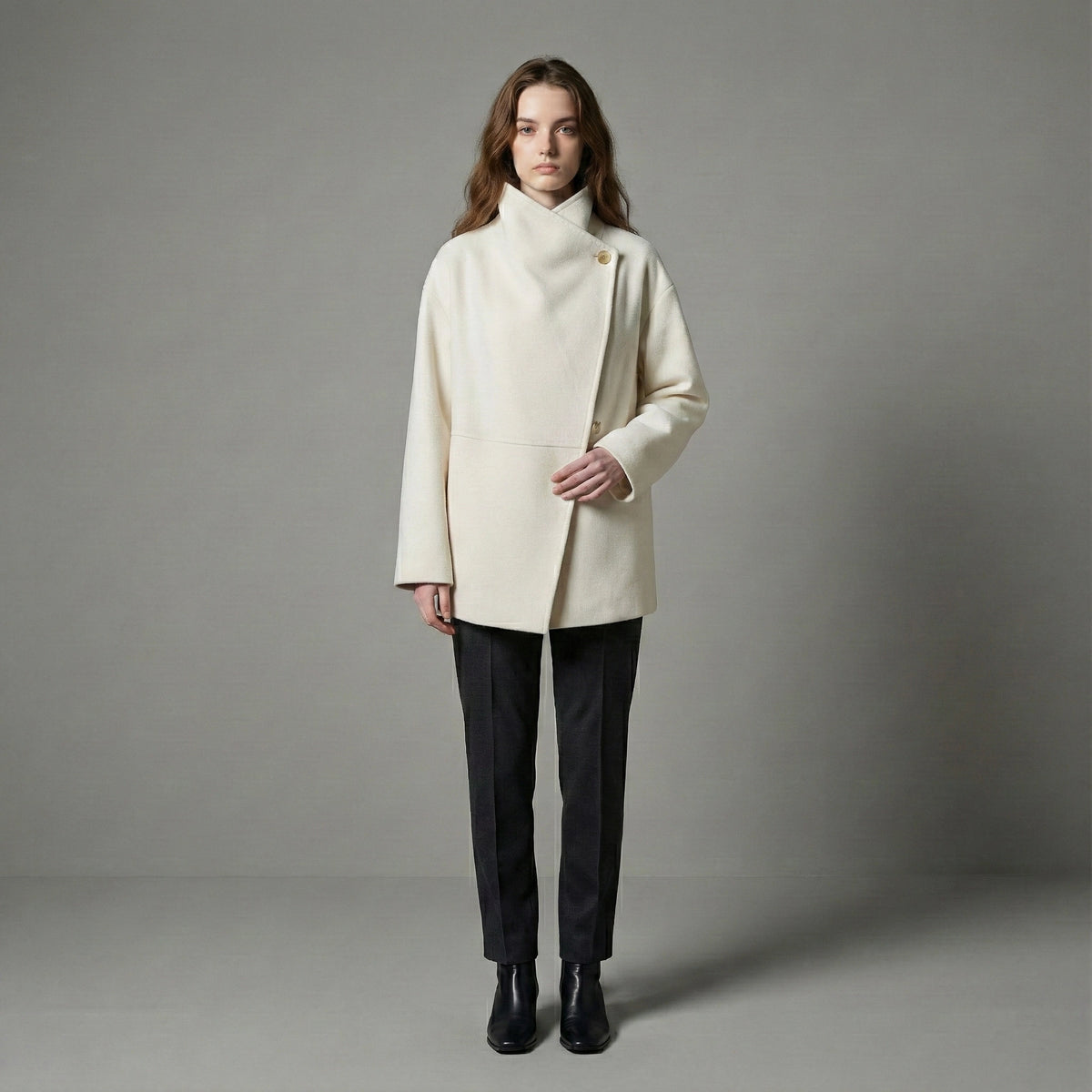 Woman wearing a cream coat against a gray background