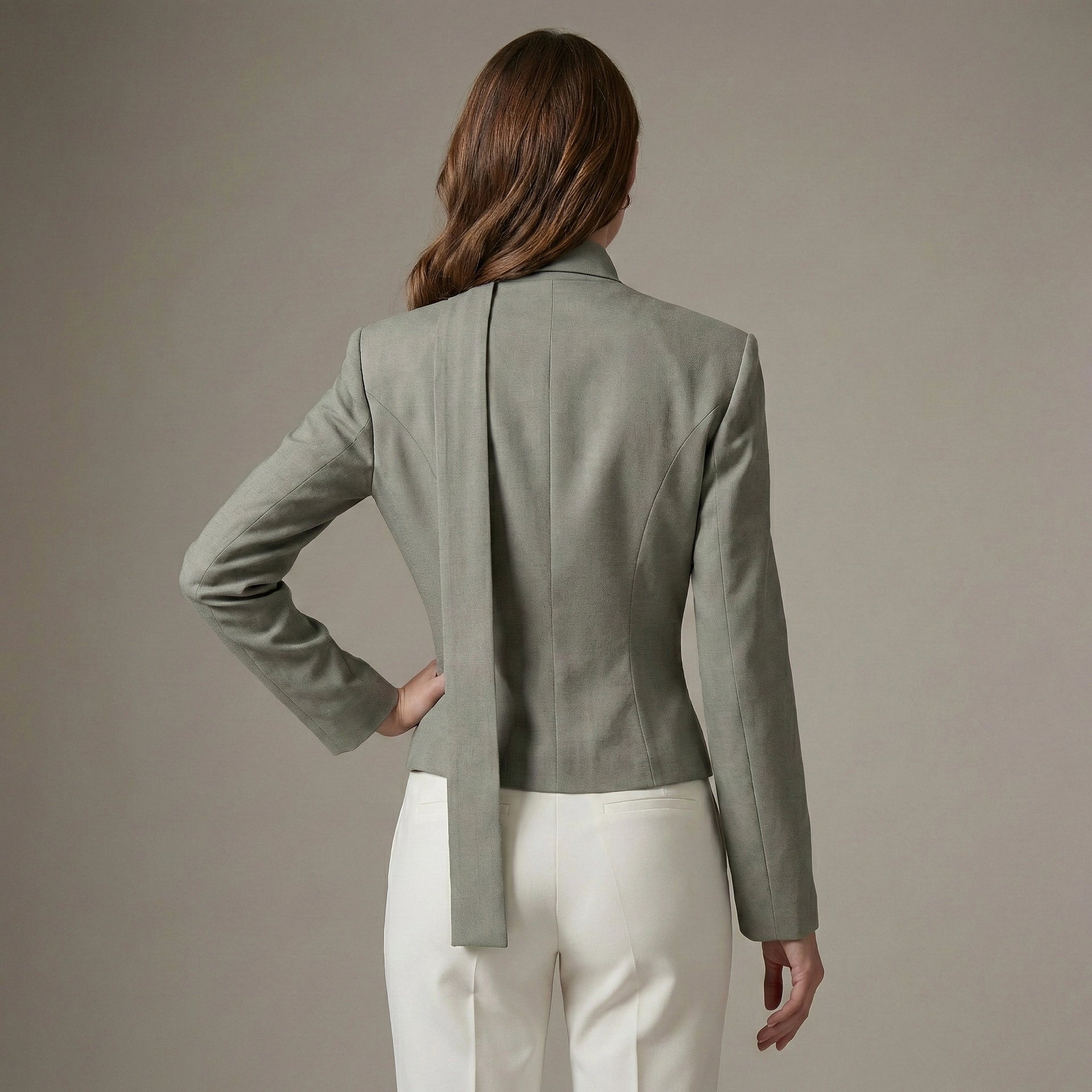 Person wearing a green blazer and white pants against a neutral background