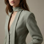 Woman wearing a light green blazer against a neutral background