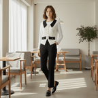 Woman in a white blouse with black collar and black pants standing in a modern cafe.
