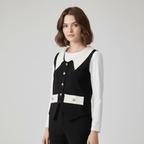 Woman wearing a black vest over a white shirt on a gray background
