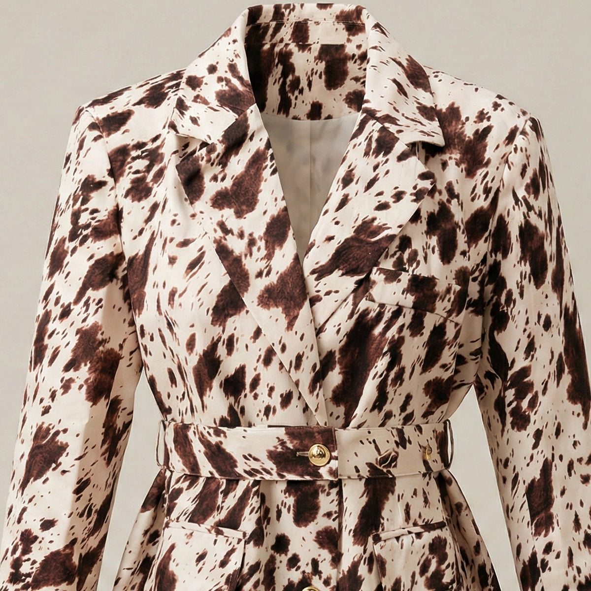 Spotted coat with a belt on a neutral background