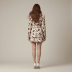 Woman wearing a patterned dress standing against a plain background