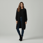 Woman wearing a black coat, black top, blue jeans, and black boots on a gray background