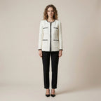 Woman wearing a white jacket with black accents and black pants on a beige background