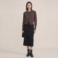 Woman wearing a brown cardigan and black skirt on a beige background