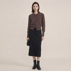 Woman wearing a brown cardigan and black skirt on a beige background