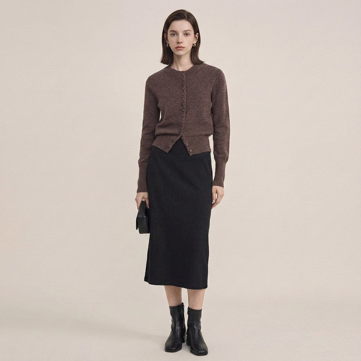 Woman wearing a brown cardigan and black skirt on a beige background