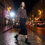 Woman walking on a city street at night with neon signs and cars in the background
