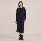Woman wearing a navy blue sweater and black skirt on a beige background