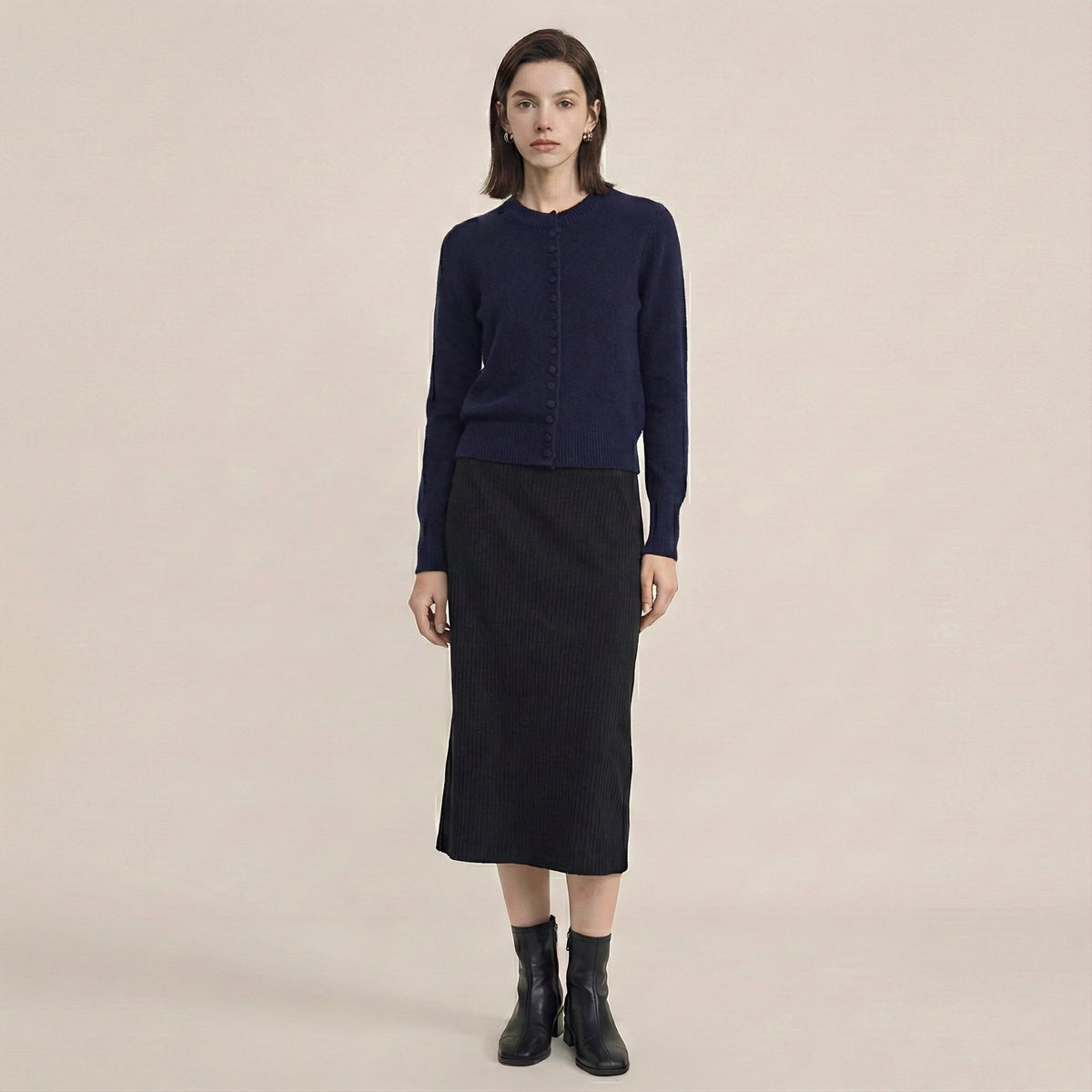 Woman wearing a navy blue sweater and black skirt on a beige background