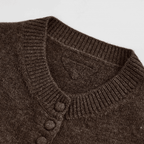 Close-up of a brown knitted cardigan with buttons on a light gray background