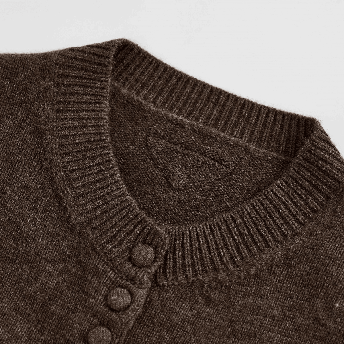 Close-up of a brown knitted cardigan with buttons on a light gray background