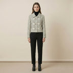 Woman wearing a checkered jacket and black pants against a beige background