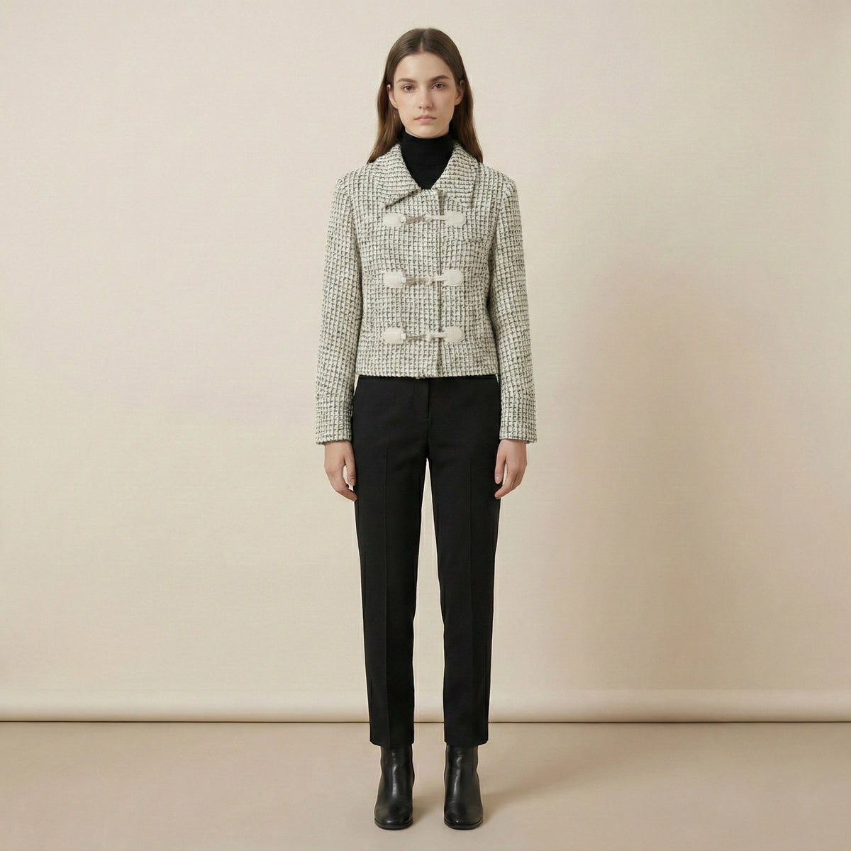 Woman wearing a checkered jacket and black pants against a beige background