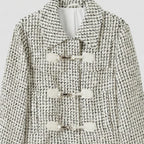 Black and white patterned coat with button details on a light gray background