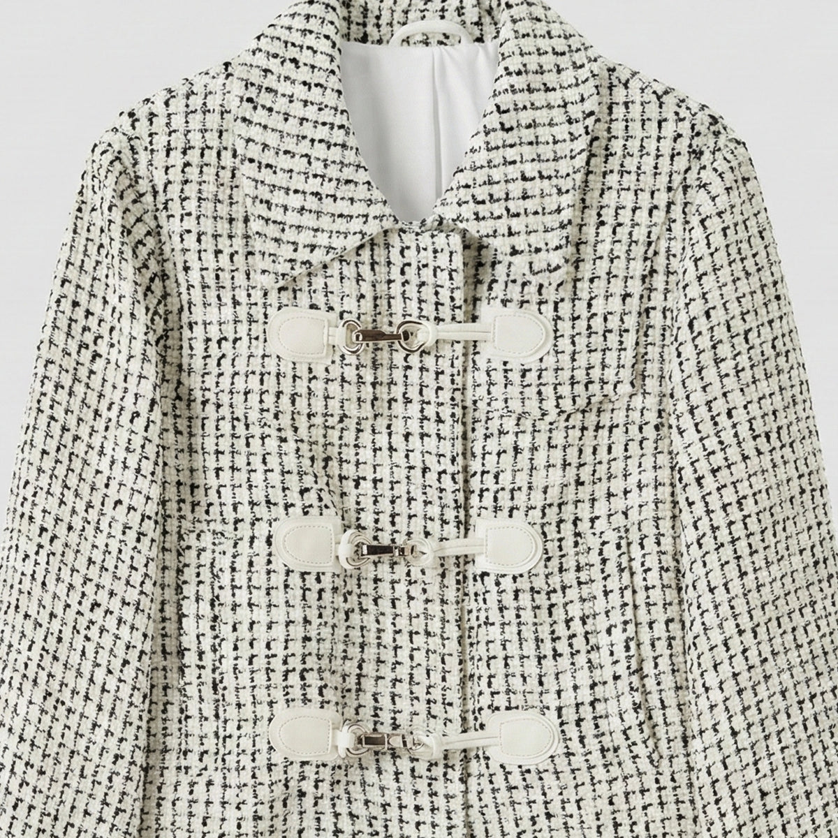 Black and white patterned coat with button details on a light gray background