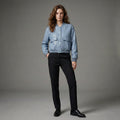Person wearing a light blue jacket and black pants on a gray background
