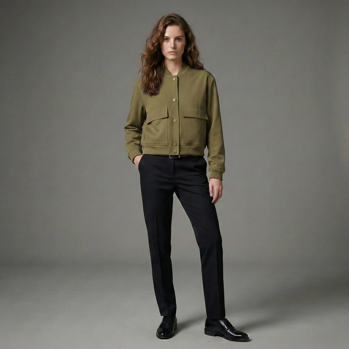 Person wearing a green jacket and black pants on a gray background