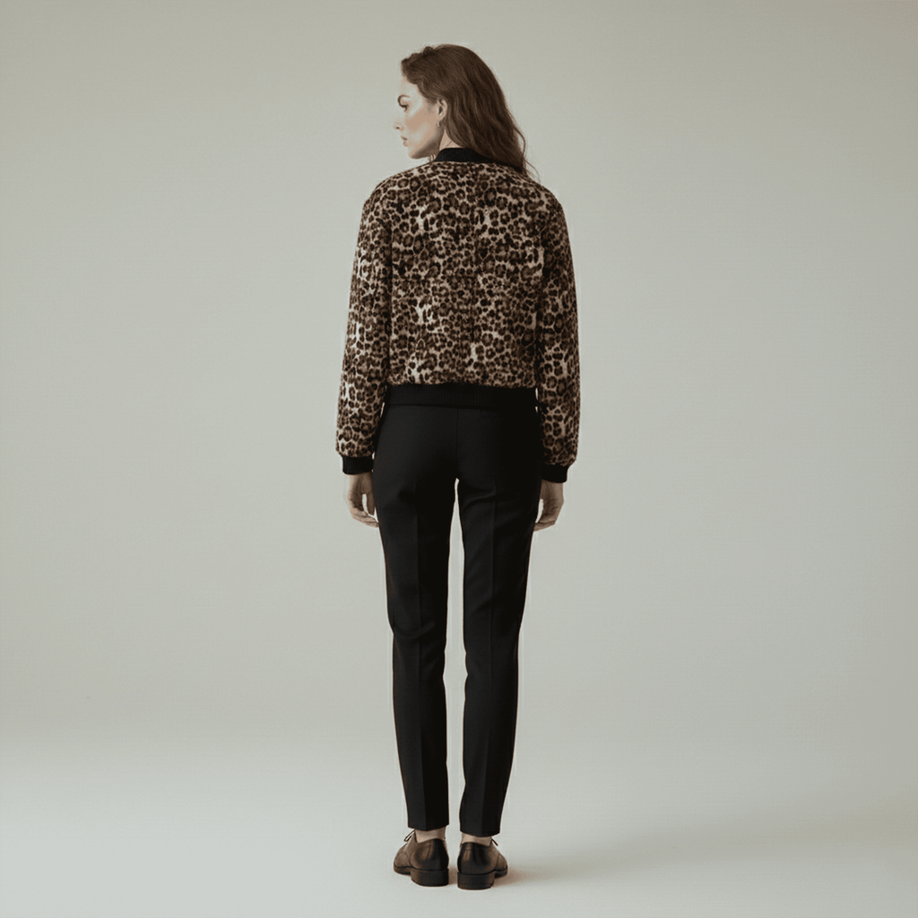 Person wearing a leopard print jacket and black pants on a plain background