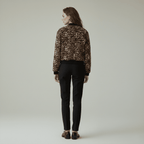 Person wearing a leopard print jacket and black pants on a plain background