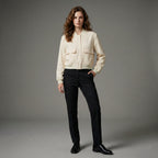 Woman wearing a cream jacket and black pants on a gray background