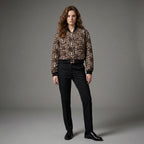 Woman wearing a leopard print blouse and black pants on a gray background