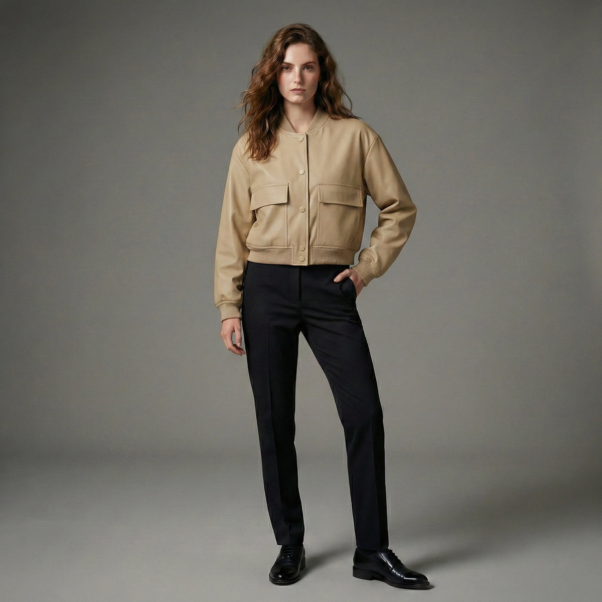 Person wearing a beige jacket and black pants on a gray background