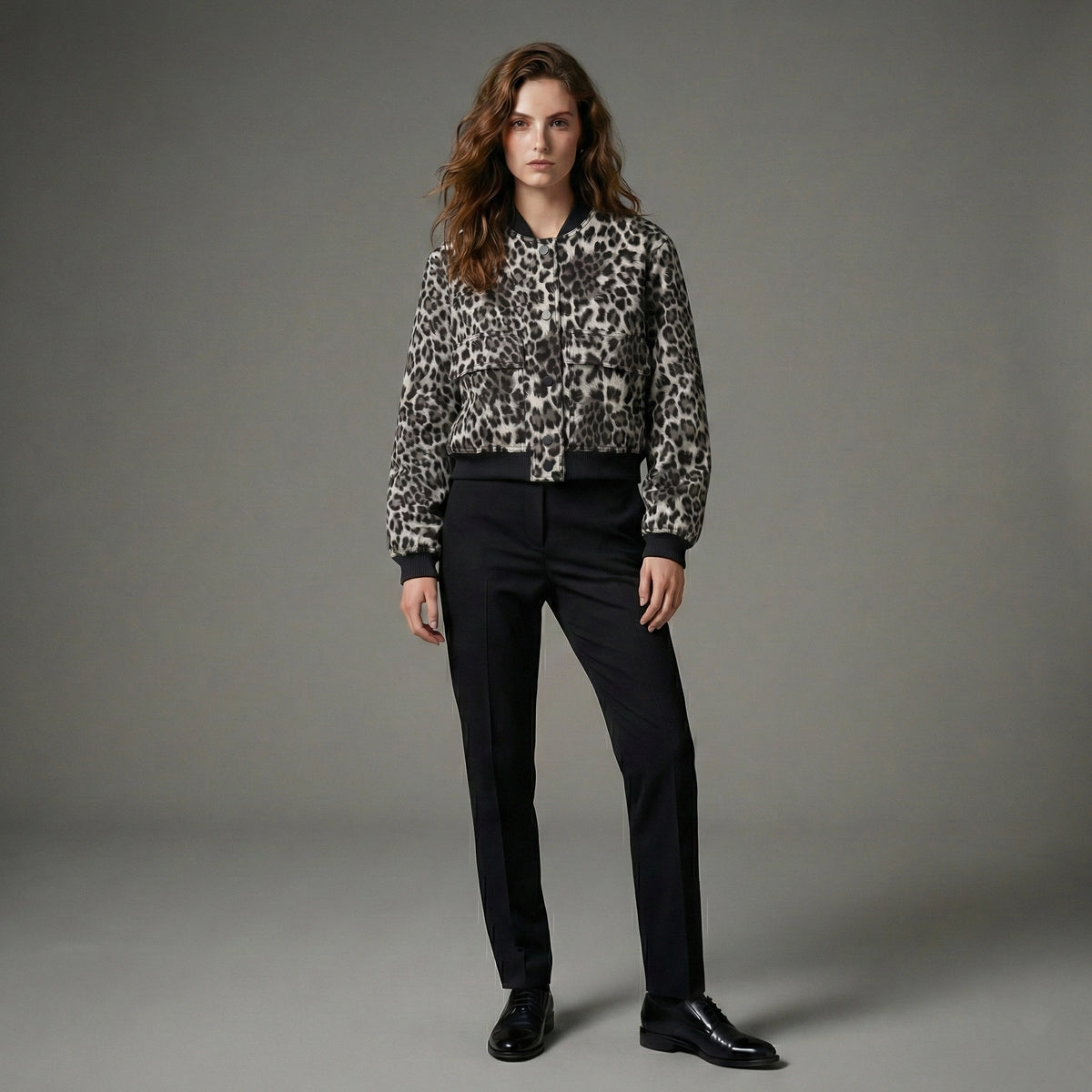 Person wearing a leopard print shirt and black pants on a gray background