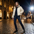 Woman in a beige puffer jacket standing on a city street at night.