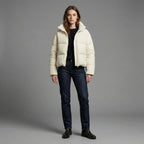 Woman wearing a cream puffer jacket against a gray background