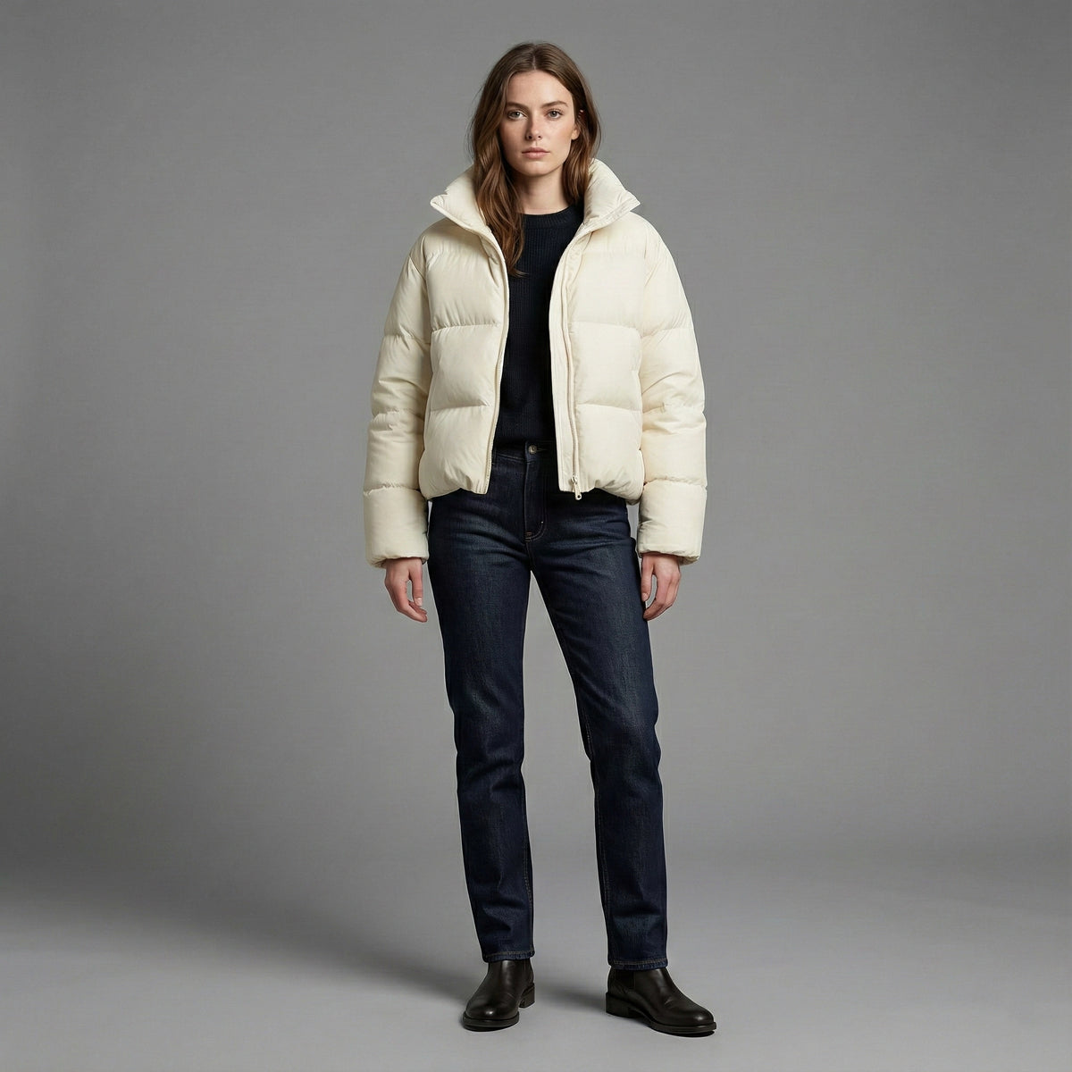Woman wearing a cream puffer jacket against a gray background