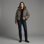 Person wearing a brown puffer jacket and dark jeans on a gray background