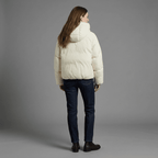 Person wearing a white puffer jacket and dark jeans on a gray background
