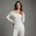 Woman wearing a white off-shoulder top and pants against a gray background
