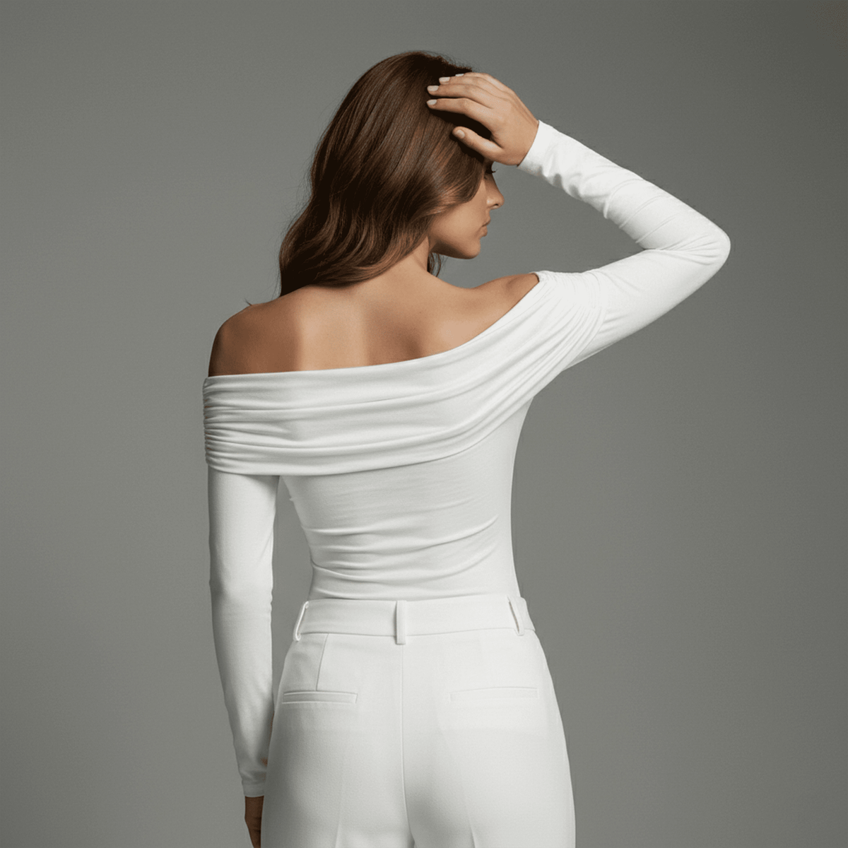 Woman wearing a white off-shoulder top and pants against a gray background