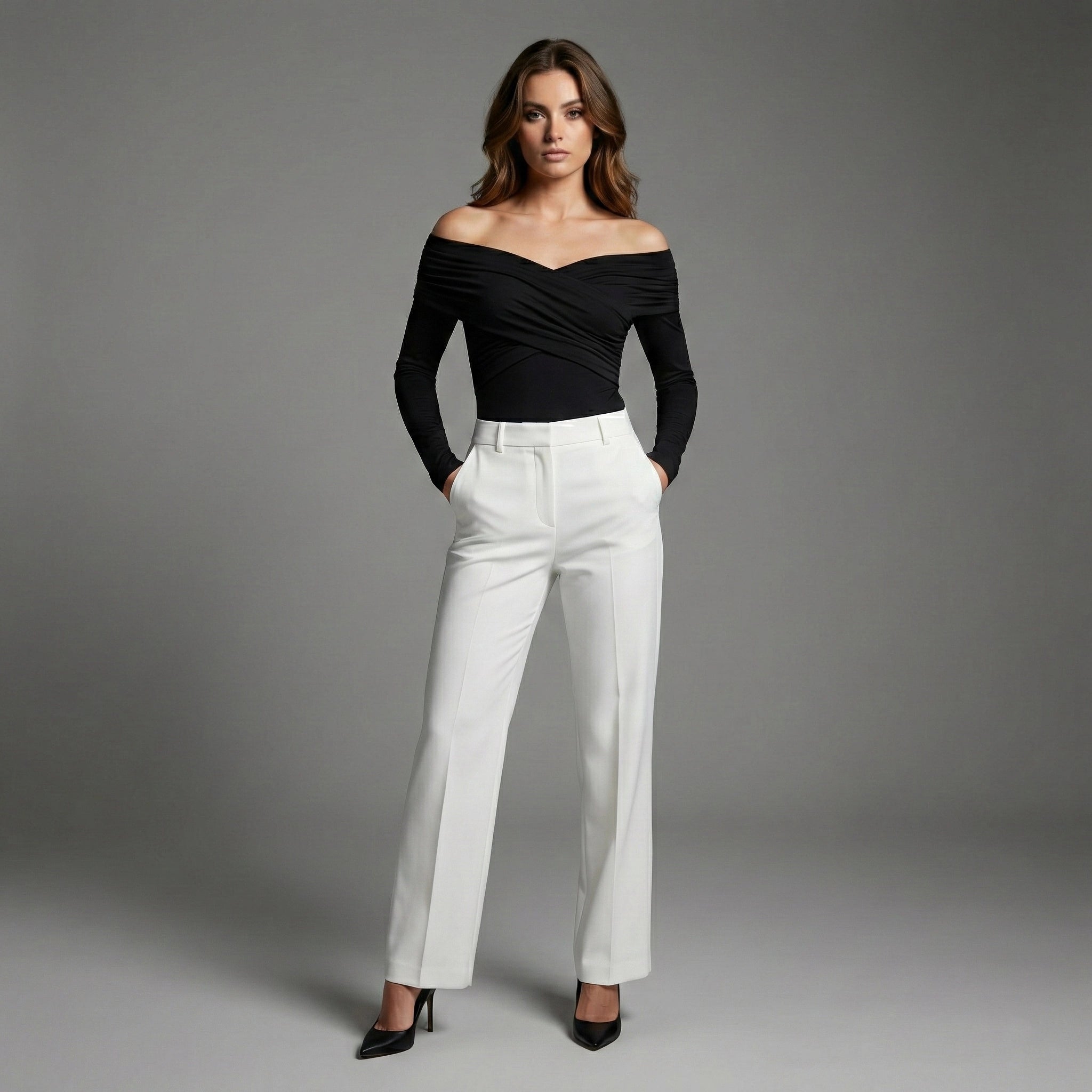 Woman wearing a black off-shoulder top and white pants against a gray background