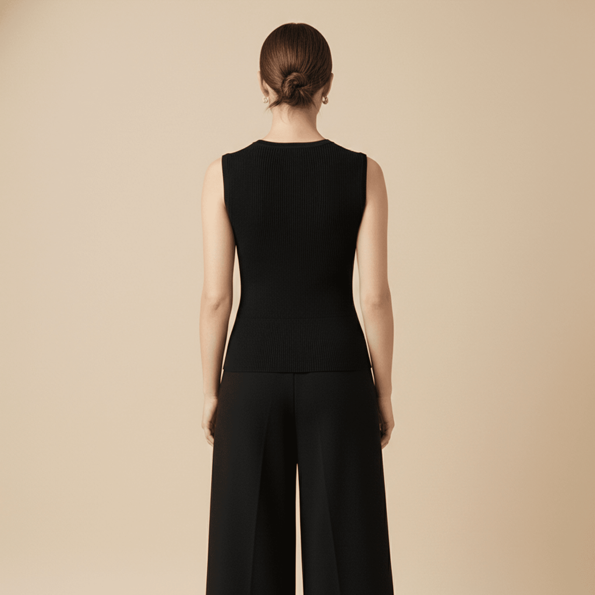 Person wearing a black sleeveless top and wide-leg pants on a beige background