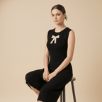 Woman wearing a black sleeveless top with a bow design, sitting on a beige background