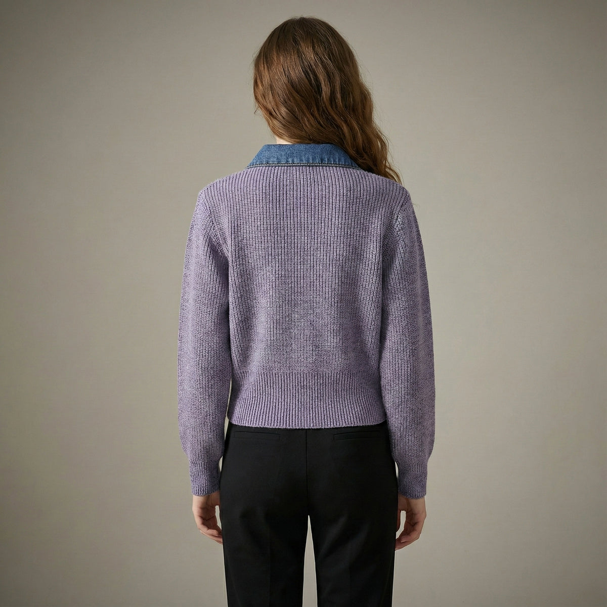Person wearing a purple sweater with a blue collar against a neutral background