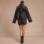 Person wearing a patterned coat and black boots on a beige background