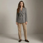 Woman wearing a checkered blazer and beige pants against a plain background